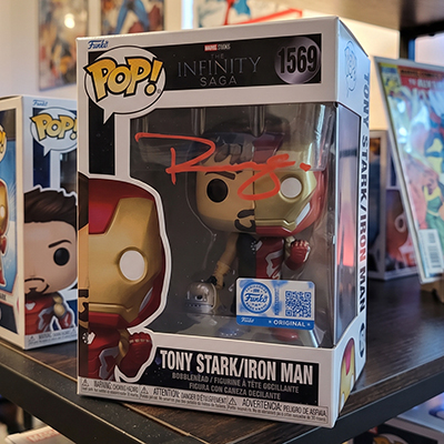 Illustration of a boxed vinyl collectible signed in red paint pen across the window, with a hologram authentication sticker